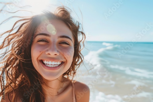Beautiful young woman is smiling at the beachside, delightfully enjoying a sunny day. Capture the essence of her healthy lifestyle and laughter © Attasit