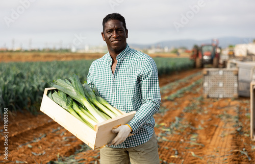 African american man with a box of leeks in the field
