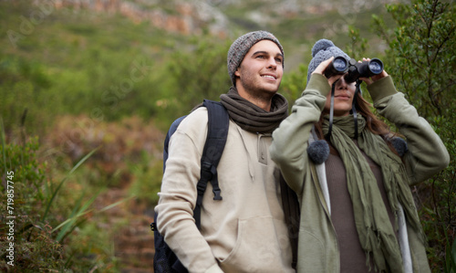 Couple, travel in nature and binoculars for hiking, adventure and journey or explore together in eco friendly mountains. Happy man and woman trekking with outdoor search, vision or birdwatching lens