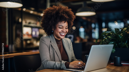African American businesswoman smiles while dedicatedly working on her laptop