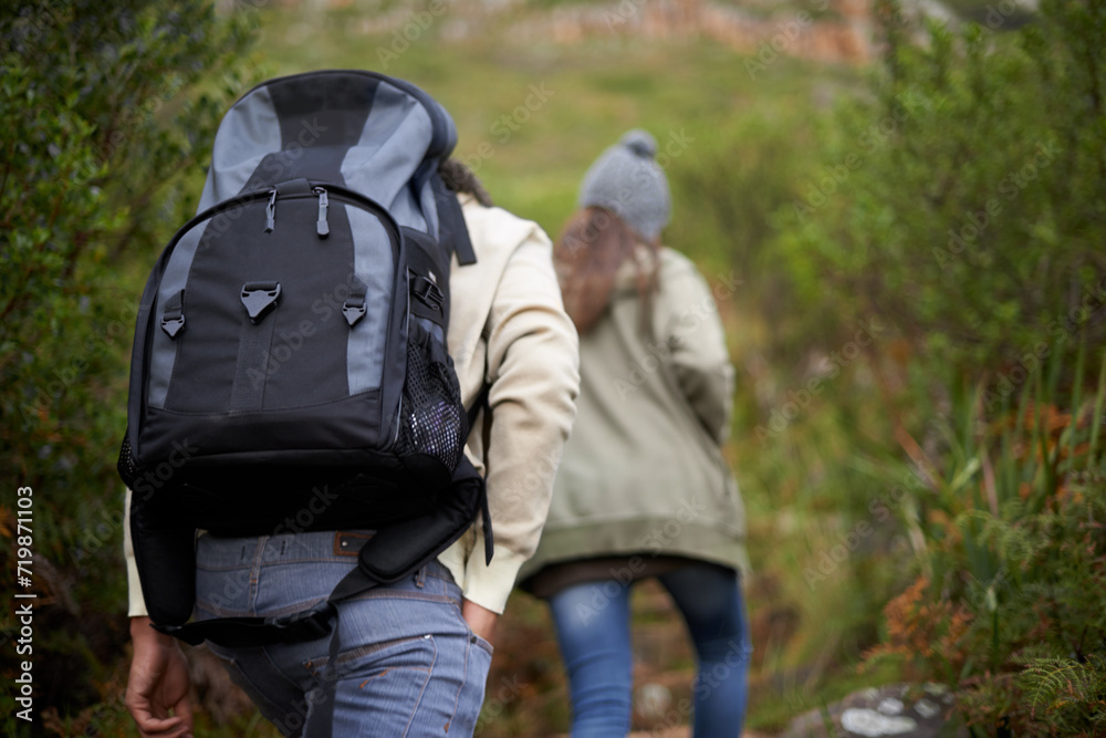 Couple of friends, hiking in nature for travel, outdoor adventure or journey in forest or eco friendly woods. Back of people walking together or trekking in backpack on mountains path to explore