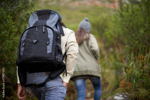 Couple of friends, hiking in nature for travel, outdoor adventure or journey in forest or eco friendly woods. Back of people walking together or trekking in backpack on mountains path to explore