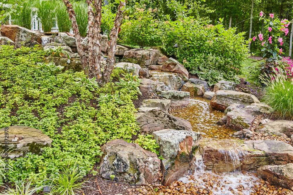 Serene Garden Waterfall with Lush Greens and Pink Flowers