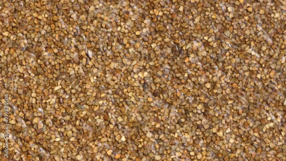 Water running down brown textured stone or concrete with pebbles. Full frame abstract texture background. Water running down brown textured stone or concrete with pebbles. Full frame abstract texture background.