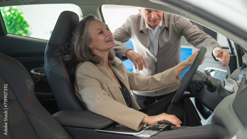 An elderly couple chooses a new car at a car dealership. Mature woman driving.  © Михаил Решетников