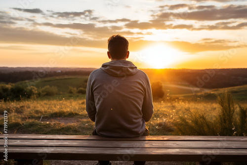 Young man sitting at a table and looking at the beautiful sunset.