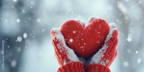 A person holding a red heart in the snow. Perfect for Valentine's Day or romantic-themed designs