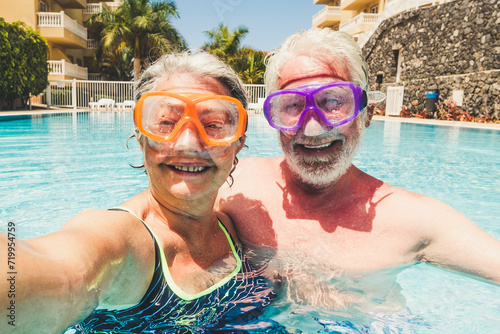Funny couple of mature people take selfie picutre while enojy and have fun at the pool in residence - elderly retired happy lifestyle with aged couple in summer leisure activity together © simona