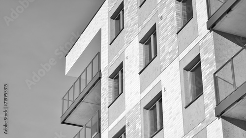 Fragment of the building's facade with windows and balconies. Modern apartment buildings on a sunny day. Facade of a modern residential building. Black and white.