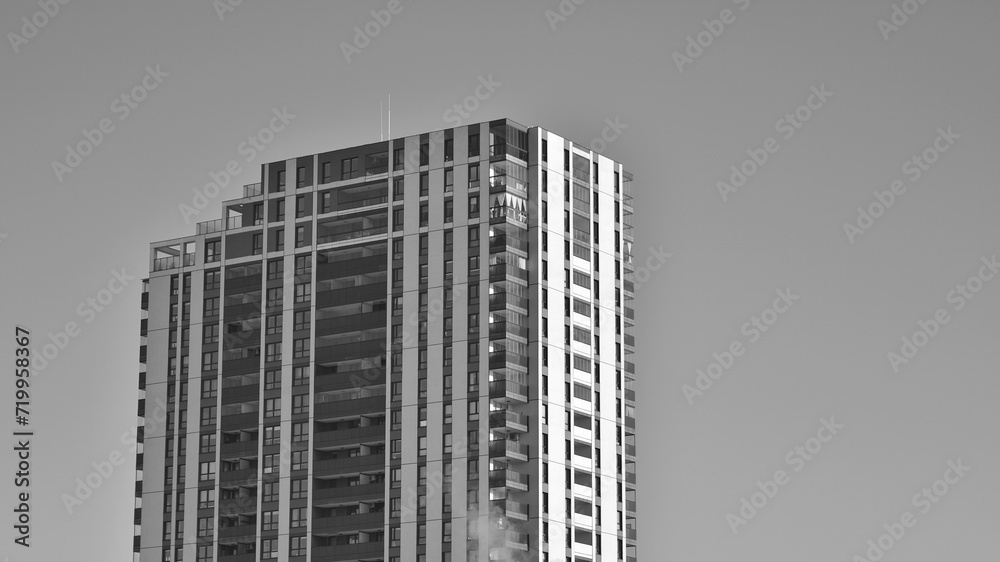 Fragment of the building's facade with windows and balconies. Modern apartment buildings on a sunny day. Facade of a modern residential building. Black and white.