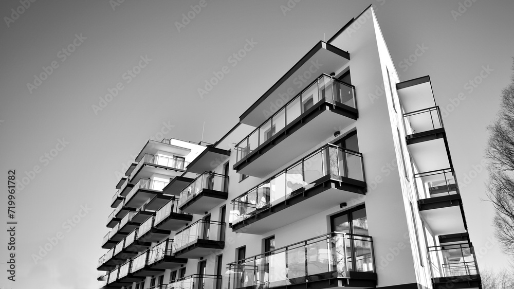Fragment of a facade of a building with windows and balconies. Modern apartment buildings on a sunny day. Facade of a modern apartment building. Black and white.