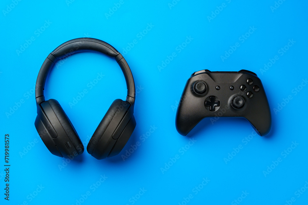 Headphones and joystick on blue background top view Headphones and joystick on blue background top view