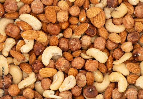 Different nuts in a heap texture background. Peanuts, almonds, hazelnuts and cashews mixed. Nuts pattern
