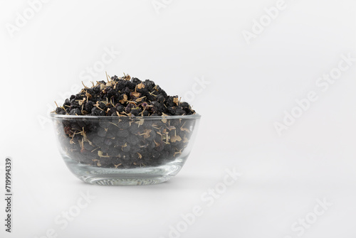 Black wolfberry or black goji berry in clear glass cup on isolated white background.