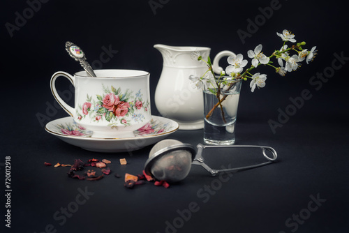 Still life with a beautiful fine china tea cup and tea accessories on a black background