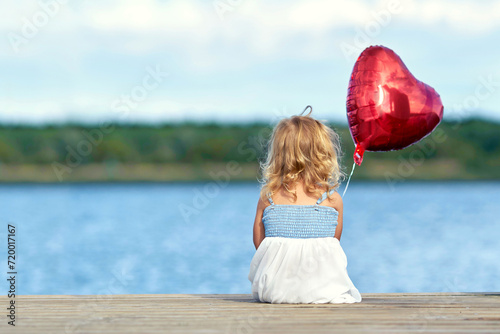 niedliches Mädchen mit Herzballon am See