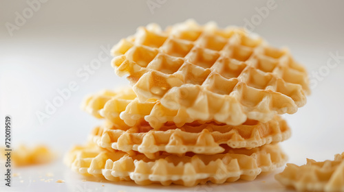 Stack of golden waffles on a bright surface.