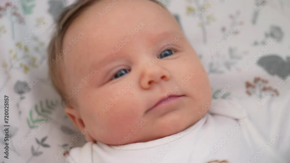 Cute baby girl with blue eyes is laying on a flowery blanket. Cute baby girl with blue eyes is laying on a flowery blanket.