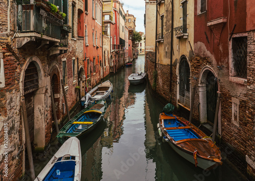Narrow channel in Venice - boats and old houses