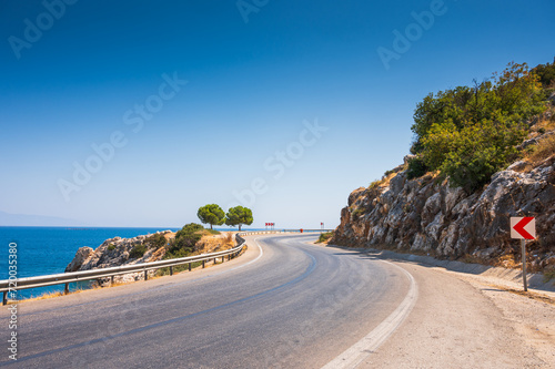 Winding road on the Mediterranean coast on the outskirts of Kemer, Antalya, Turkey. Road along the sea and mountains, sunny beautiful day. Traveling around Turkey by car along the Mediterranean Sea.