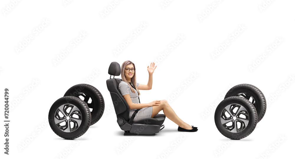 Full length shot of a young female passenger in a car seat on four tires waving Full length shot of a young female passenger in a car seat on four tires waving