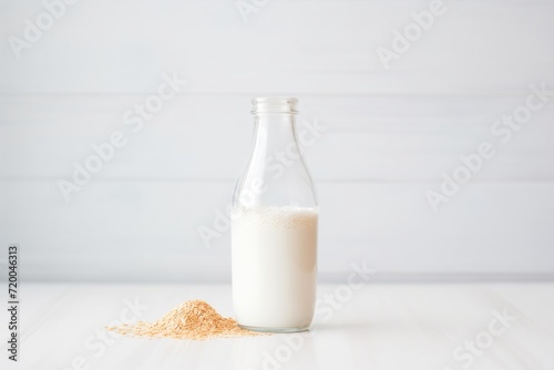 oat milk in transparent bottle, white surface