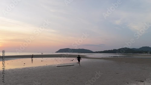 4K MAN RUNNING ON THE BEACH DURING SUNSET photo