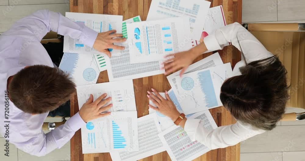Business woman and man nervously looking for document top view