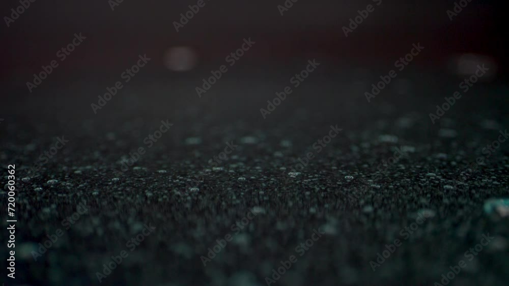 Slow-moving, transparent gel stream on a dark surface, its spatial structure and bubbles glistening under studio lighting Slow-moving, transparent gel stream on a dark surface, its spatial structure and bubbles glistening under studio lighting