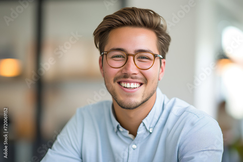 Cheerful Entrepreneur Portrait. Smiling young man with glasses, bright office backdrop.