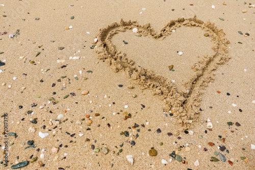 drawn heart in the sand from a beach with lot of corals and stones