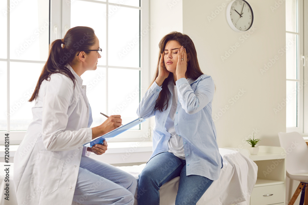 Obraz premium Young brunette pregnant woman visiting her gynecologist doctor in hospital or medical clinic and feel stressed, migraine and suffering from headache. Pregnancy and healthcare concept.