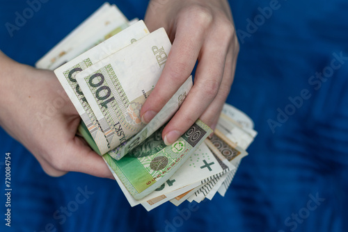 Kobieta trzyma w dłoniach pieniądze, liczy polskie banknoty