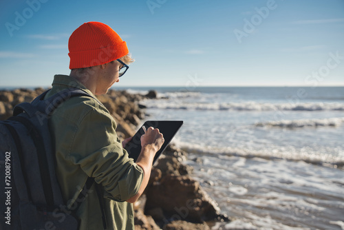 Young marine biologist studying marine fauna with an electronic tablet on the seashore. Control of the environment. photo