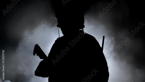 Military soldier in army camouflage stands, silhouette warrior with weapon assault rifle carbine. Shadow of mercenary in uniform and helmet. War concept. Private military company. Fog smoke background photo