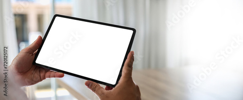 A businessman holds a mockup. iPad digital tablet with blank screen Mockup replaces your design mockup in the office.