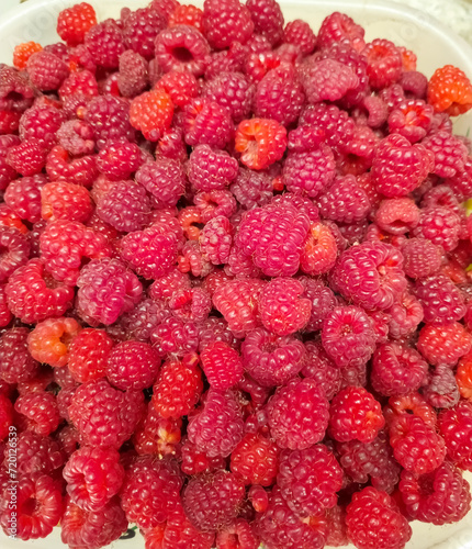 Close-up - a lot of ripe raspberries in a cup