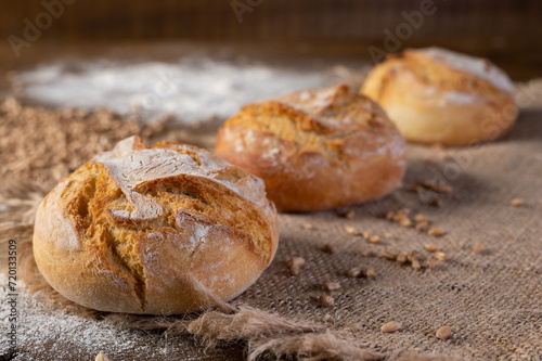 Bakery - Round bread close up. Freshly baked bread with a golden crust on rustic wooden background.