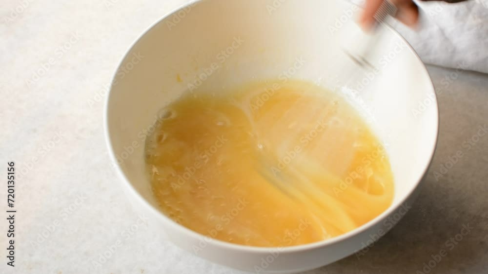 Whisking eggs and sugar together until pale, mixing eggs and sugar by hand, process of making a cake Whisking eggs and sugar together until pale, mixing eggs and sugar by hand, process of making a cake