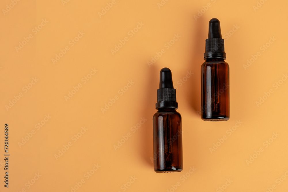 Cosmetic bottles made of dark amber glass on cream background Cosmetic bottles made of dark amber glass on cream background