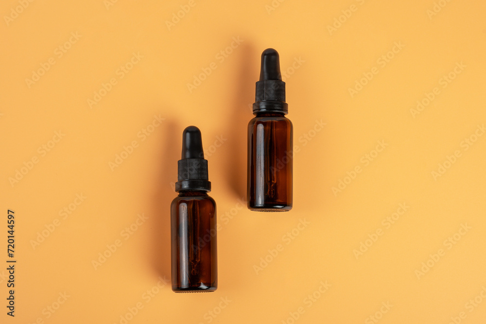 Cosmetic bottles made of dark amber glass on cream background Cosmetic bottles made of dark amber glass on cream background