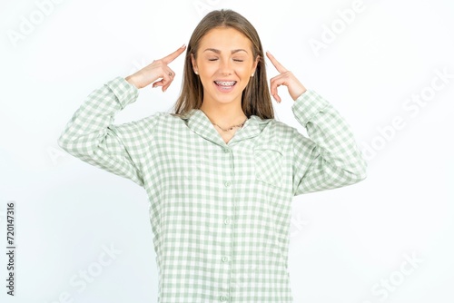 Photo of crazy Beautiful young woman wearing green plaid pyjama screaming and pointing with fingers at hair closed eyes