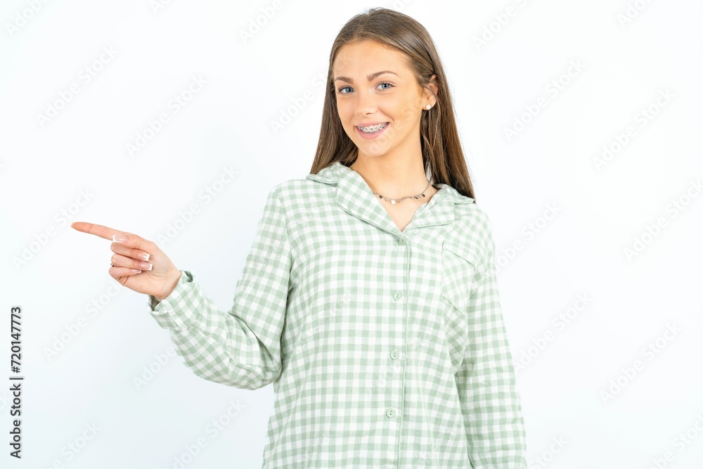 Beautiful young woman wearing green plaid pyjama points aside on copy blank space. People promotion and advertising concept Beautiful young woman wearing green plaid pyjama points aside on copy blank space. People promotion and advertising concept