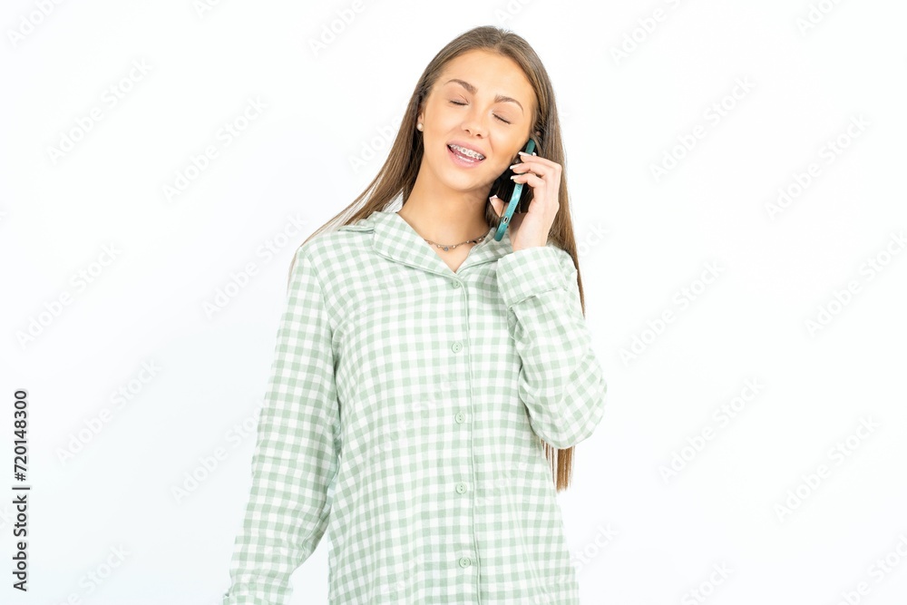 Funny Beautiful young woman wearing green plaid pyjama laughs happily, has phone conversation, being amused by friend, closes eyes. Funny Beautiful young woman wearing green plaid pyjama laughs happily, has phone conversation, being amused by friend, closes eyes.