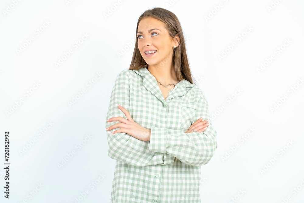 Young beautiful woman standing over white studio background arms crossed look empty space billboard Young beautiful woman standing over white studio background arms crossed look empty space billboard