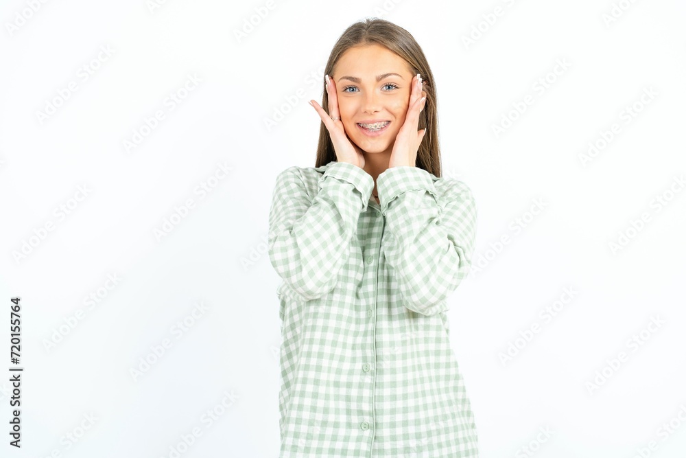 Happy Young beautiful woman standing over white studio background touches both cheeks gently, has tender smile, shows white teeth, gazes positively straightly at camera, Happy Young beautiful woman standing over white studio background touches both cheeks gently, has tender smile, shows white teeth, gazes positively straightly at camera,
