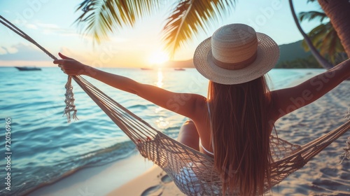 Fototapeta Naklejka Na Ścianę i Meble -  Summer vacations concept, Happy woman with white bikini, hat and shorts Jeans relaxing in hammock on tropical beach at sunset