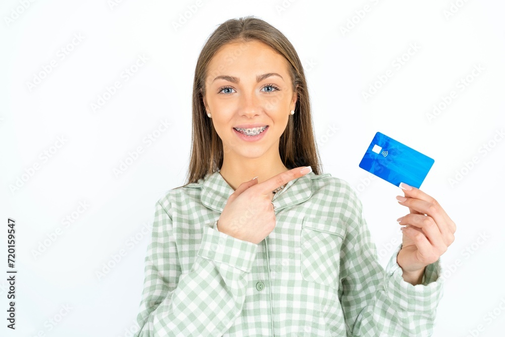 Photo portrait of young beautiful woman wearing green plaid pyjama, doing purchase with pointing finger credit bank card Photo portrait of young beautiful woman wearing green plaid pyjama, doing purchase with pointing finger credit bank card