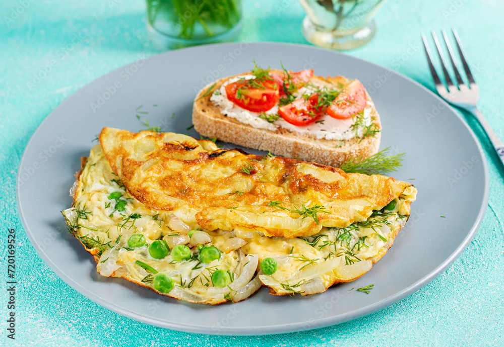 Omelette with green peas, onions and toast cream cheese, tomatoes on blue plate. Frittata - italian omelet. Omelette with green peas, onions and toast cream cheese, tomatoes on blue plate. Frittata - italian omelet.