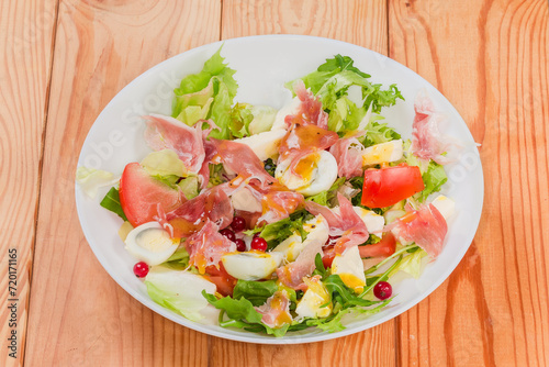 Salad of jamon with quail eggs, different greens and vegetables